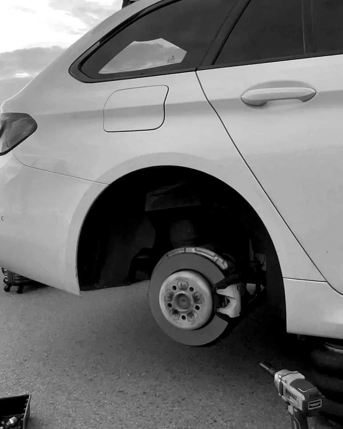 Zdjęte tylne koło BMW podczas mobilnej wymiany o zachodzie słońca